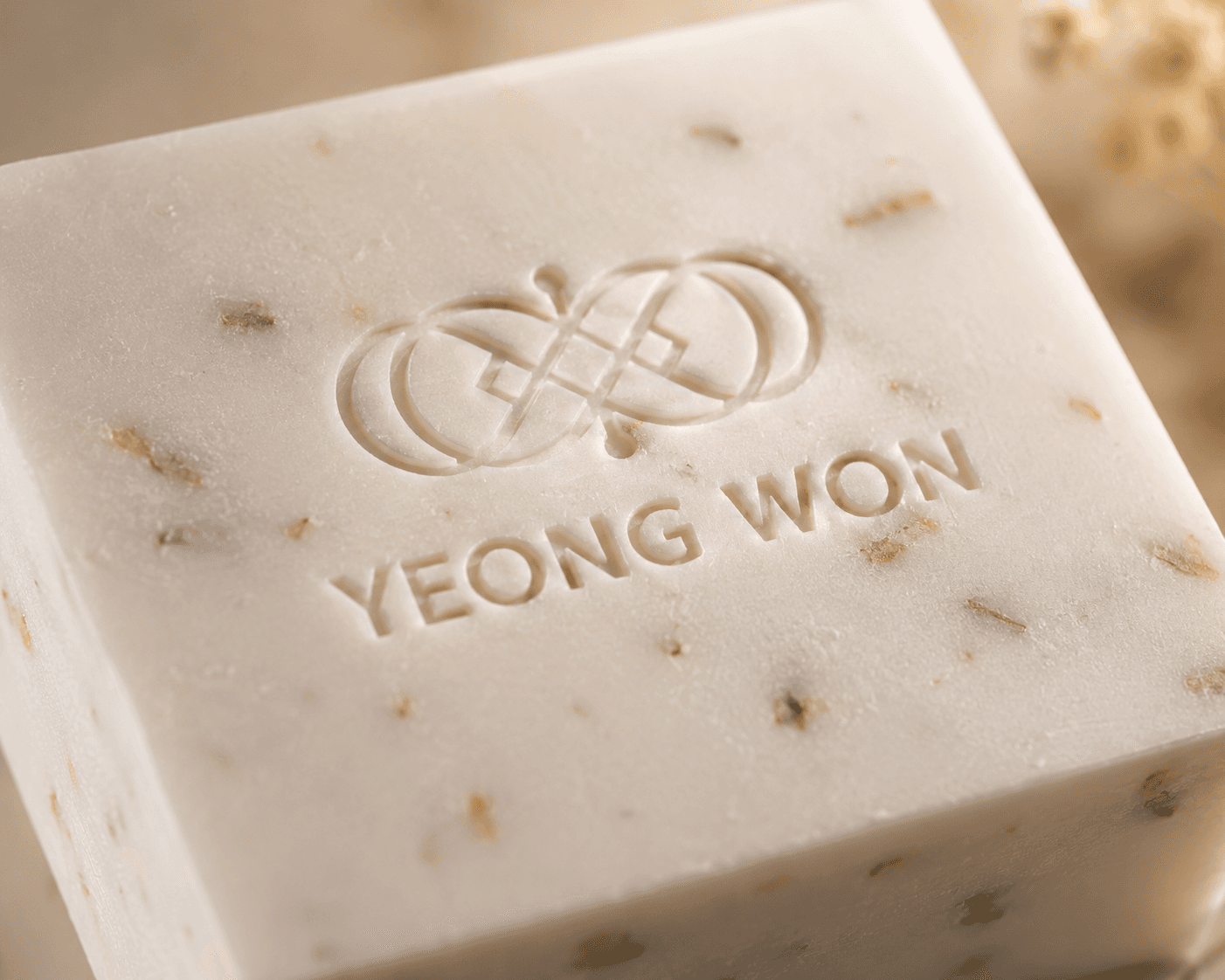Macro of the Yeong Won soap bar surface, embossed logo and flecks of oat and botanicals